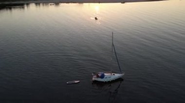 Mavi denizde yüksek hızda seyreden lüks sürat teknesinin fotokopi uzayına sahip bir hava aracı. Yelkenli yatın ve suda altın gün batımının yansıması. Okyanustaki denizcilik gemisinde boş zaman.