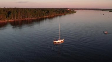 Mavi denizde yüksek hızda seyreden lüks sürat teknesinin fotokopi uzayına sahip bir hava aracı. Yelkenli yatın ve suda altın gün batımının yansıması. Okyanustaki denizcilik gemisinde boş zaman.
