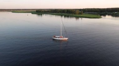Mavi denizde yüksek hızda seyreden lüks sürat teknesinin fotokopi uzayına sahip bir hava aracı. Yelkenli yatın ve suda altın gün batımının yansıması. Okyanustaki denizcilik gemisinde boş zaman.