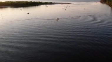 Gün batımında nehirde kayak yapan bir grup insanın hava aracı görüntüsü. Yaz tatilinde deniz kenarında su sporu yapan turistler. Akşamları kano sürerler. Sağlıklı bir yaşam tarzı. Etkin seyahat 