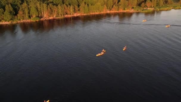 日没時に川でカヤックの人々のグループの空中ドローンビュー 夏休みの海で水上スポーツをする船の観光客 夕方にカヤックを漕ぐ 健康的なライフスタイル アクティブな旅行 — ストック動画