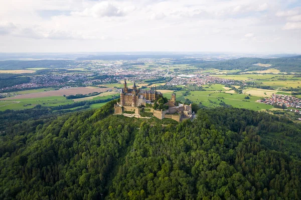 Drone shot of Hohenzollern Castle on forested mountain top in the Swabian Alps in summer. Scenic aerial view of old German Burg. Famous fairytale Gothic landmark in Stuttgart vicinity