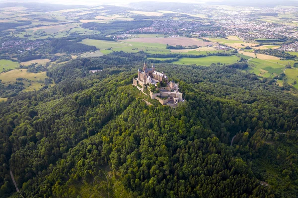 Drone shot of Hohenzollern Castle on forested mountain top in the Swabian Alps in summer. Scenic aerial view of old German Burg. Famous fairytale Gothic landmark in Stuttgart vicinity