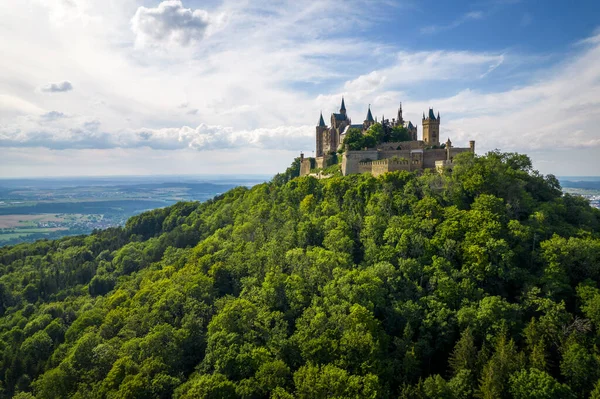 Drone shot of Hohenzollern Castle on forested mountain top in the Swabian Alps in summer. Scenic aerial view of old German Burg. Famous fairytale Gothic landmark in Stuttgart vicinity