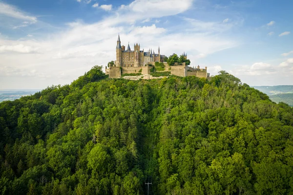 Drone shot of Hohenzollern Castle on forested mountain top in the Swabian Alps in summer. Scenic aerial view of old German Burg. Famous fairytale Gothic landmark in Stuttgart vicinity