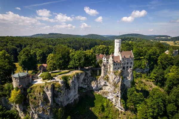 Yazın Swabian Alpleri 'ndeki orman kayalıkları üzerindeki lichtenstein kalesinin (Schloss) havadan görünüşü. Gökyüzünde Gotik diriliş tarzında romantik masal sarayının mevsimsel manzarası. Avrupa 'nın ünlü simgesi