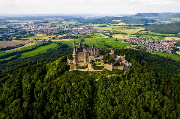 Drone shot of Hohenzollern Castle on forested mountain top in the Swabian Alps in summer. Scenic aerial view of old German Burg. Famous fairytale Gothic landmark in Stuttgart vicinity