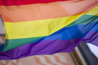 Yakın plan gökkuşağı eşcinsellik gururu bayrağı bir sokakta. Lezbiyen Biseksüel Transseksüel LGBT topluluğunun sembolü bulutlu gökyüzüne karşı rüzgarda sallanıyor. Özgürlük ve eşitlik için sosyal hareket. Boşluğu Kopyala 