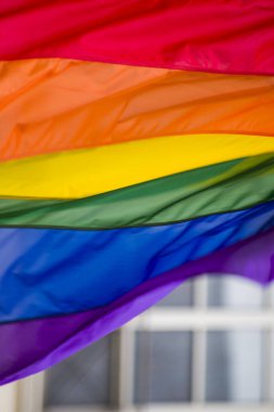 Yakın plan gökkuşağı eşcinsellik gururu bayrağı bir sokakta. Lezbiyen Biseksüel Transseksüel LGBT topluluğunun sembolü bulutlu gökyüzüne karşı rüzgarda sallanıyor. Özgürlük ve eşitlik için sosyal hareket. Boşluğu Kopyala 