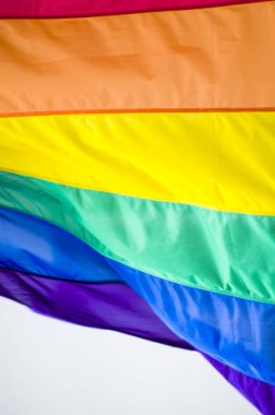 Close-Up rainbow gay pride flag outside on a street. Symbol of the Lesbian Bisexual Transgender LGBT community waving in wind against cloudy sky. Social movement for freedom and equliaty. Copy Space 