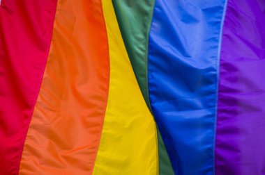 Yakın plan gökkuşağı eşcinsellik gururu bayrağı bir sokakta. Lezbiyen Biseksüel Transseksüel LGBT topluluğunun sembolü bulutlu gökyüzüne karşı rüzgarda sallanıyor. Özgürlük ve eşitlik için sosyal hareket. Boşluğu Kopyala 