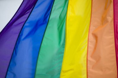 Yakın plan gökkuşağı eşcinsellik gururu bayrağı bir sokakta. Lezbiyen Biseksüel Transseksüel LGBT topluluğunun sembolü bulutlu gökyüzüne karşı rüzgarda sallanıyor. Özgürlük ve eşitlik için sosyal hareket. Boşluğu Kopyala 