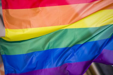 Yakın plan gökkuşağı eşcinsellik gururu bayrağı bir sokakta. Lezbiyen Biseksüel Transseksüel LGBT topluluğunun sembolü bulutlu gökyüzüne karşı rüzgarda sallanıyor. Özgürlük ve eşitlik için sosyal hareket. Boşluğu Kopyala 
