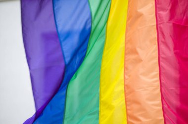 Yakın plan gökkuşağı eşcinsellik gururu bayrağı bir sokakta. Lezbiyen Biseksüel Transseksüel LGBT topluluğunun sembolü bulutlu gökyüzüne karşı rüzgarda sallanıyor. Özgürlük ve eşitlik için sosyal hareket. Boşluğu Kopyala 