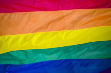 Yakın plan gökkuşağı eşcinsellik gururu bayrağı bir sokakta. Lezbiyen Biseksüel Transseksüel LGBT topluluğunun sembolü bulutlu gökyüzüne karşı rüzgarda sallanıyor. Özgürlük ve eşitlik için sosyal hareket. Boşluğu Kopyala 