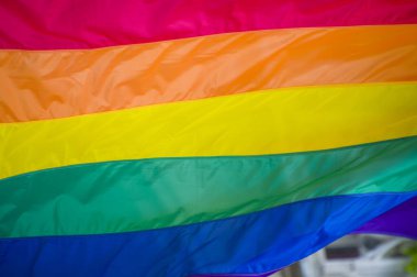 Yakın plan gökkuşağı eşcinsellik gururu bayrağı bir sokakta. Lezbiyen Biseksüel Transseksüel LGBT topluluğunun sembolü bulutlu gökyüzüne karşı rüzgarda sallanıyor. Özgürlük ve eşitlik için sosyal hareket. Boşluğu Kopyala 