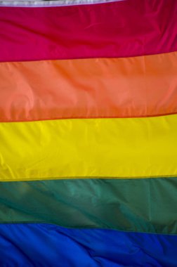 Yakın plan gökkuşağı eşcinsellik gururu bayrağı bir sokakta. Lezbiyen Biseksüel Transseksüel LGBT topluluğunun sembolü bulutlu gökyüzüne karşı rüzgarda sallanıyor. Özgürlük ve eşitlik için sosyal hareket. Boşluğu Kopyala 