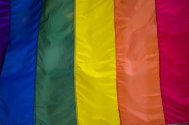 Yakın plan gökkuşağı eşcinsellik gururu bayrağı bir sokakta. Lezbiyen Biseksüel Transseksüel LGBT topluluğunun sembolü bulutlu gökyüzüne karşı rüzgarda sallanıyor. Özgürlük ve eşitlik için sosyal hareket. Boşluğu Kopyala 