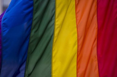 Yakın plan gökkuşağı eşcinsellik gururu bayrağı bir sokakta. Lezbiyen Biseksüel Transseksüel LGBT topluluğunun sembolü bulutlu gökyüzüne karşı rüzgarda sallanıyor. Özgürlük ve eşitlik için sosyal hareket. Boşluğu Kopyala 