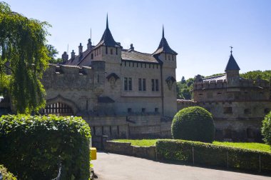 Lihtenştayn Şatosu 'nun ya da Schloss' un yazın Swabian Alpleri 'ndeki ormanlık kayalıklardaki fotoğrafı. Gökyüzünde Gotik diriliş tarzında romantik masal sarayının mevsimsel manzarası. Avrupa 'nın ünlü simgesi