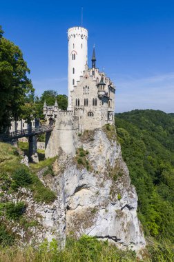 Lihtenştayn Şatosu 'nun ya da Schloss' un yazın Swabian Alpleri 'ndeki ormanlık kayalıklardaki fotoğrafı. Gökyüzünde Gotik diriliş tarzında romantik masal sarayının mevsimsel manzarası. Avrupa 'nın ünlü simgesi