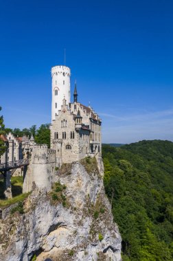 Lihtenştayn Şatosu 'nun ya da Schloss' un yazın Swabian Alpleri 'ndeki ormanlık kayalıklardaki fotoğrafı. Gökyüzünde Gotik diriliş tarzında romantik masal sarayının mevsimsel manzarası. Avrupa 'nın ünlü simgesi