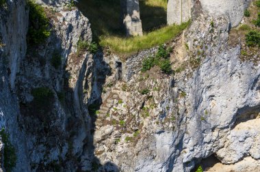 Photo of lichtenstein castle or Schloss on forested rock cliff in Swabian Alps in summer. Seasonal panorama of romantic fairytale palace in Gothic revival style over sky. European famous landmark