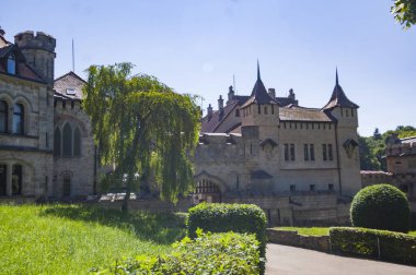 Lihtenştayn Şatosu 'nun ya da Schloss' un yazın Swabian Alpleri 'ndeki ormanlık kayalıklardaki fotoğrafı. Gökyüzünde Gotik diriliş tarzında romantik masal sarayının mevsimsel manzarası. Avrupa 'nın ünlü simgesi