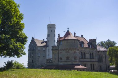Lihtenştayn Şatosu 'nun ya da Schloss' un yazın Swabian Alpleri 'ndeki ormanlık kayalıklardaki fotoğrafı. Gökyüzünde Gotik diriliş tarzında romantik masal sarayının mevsimsel manzarası. Avrupa 'nın ünlü simgesi