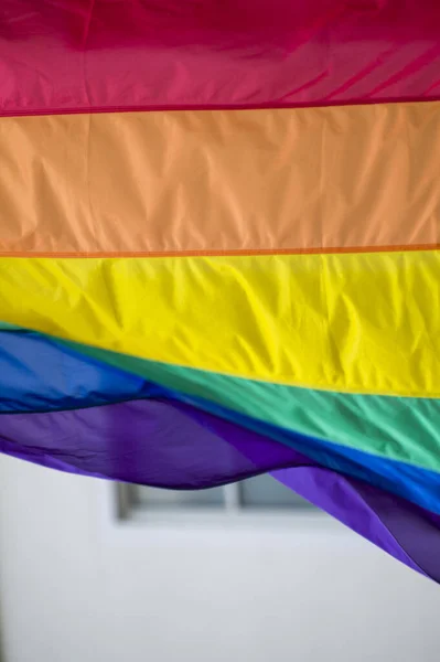 Close-Up rainbow gay pride flag outside on a street. Symbol of the Lesbian Bisexual Transgender LGBT community waving in wind against cloudy sky. Social movement for freedom and equliaty. Copy Space