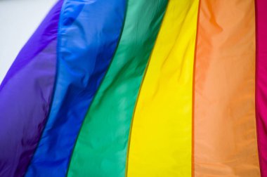 Yakın plan gökkuşağı eşcinsellik gururu bayrağı bir sokakta. Lezbiyen Biseksüel Transseksüel LGBT topluluğunun sembolü bulutlu gökyüzüne karşı rüzgarda sallanıyor. Özgürlük ve eşitlik için sosyal hareket. Boşluğu Kopyala 