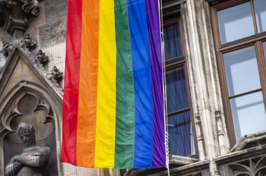 Close-Up rainbow gay pride flag outside on a street. Symbol of the Lesbian Bisexual Transgender LGBT community waving in wind against cloudy sky. Social movement for freedom and equliaty. Copy Space 