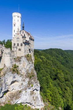 Lihtenştayn Şatosu 'nun ya da Schloss' un yazın Swabian Alpleri 'ndeki ormanlık kayalıklardaki fotoğrafı. Gökyüzünde Gotik diriliş tarzında romantik masal sarayının mevsimsel manzarası. Avrupa 'nın ünlü simgesi