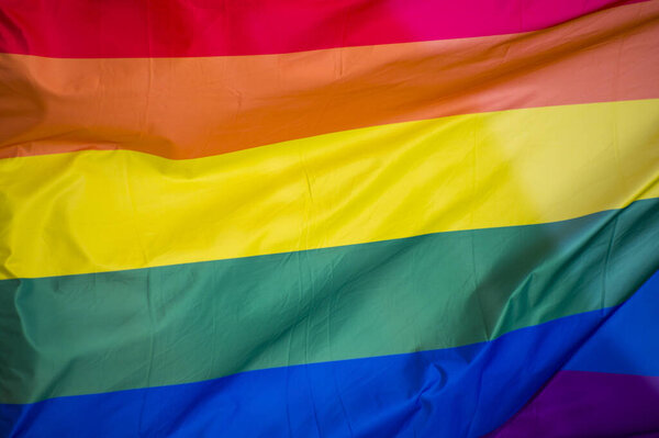 Крупный план радужного гей-флага на улице. Символ ЛГБТ-сообщества лесбиянок-бисексуалов, размахивающих ветром против облачного неба. Социальное движение за свободу и равновесие. Копировальное пространство 