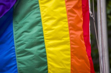 Yakın plan gökkuşağı eşcinsellik gururu bayrağı bir sokakta. Lezbiyen Biseksüel Transseksüel LGBT topluluğunun sembolü bulutlu gökyüzüne karşı rüzgarda sallanıyor. Özgürlük ve eşitlik için sosyal hareket. Boşluğu Kopyala 