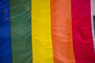 Yakın plan gökkuşağı eşcinsellik gururu bayrağı bir sokakta. Lezbiyen Biseksüel Transseksüel LGBT topluluğunun sembolü bulutlu gökyüzüne karşı rüzgarda sallanıyor. Özgürlük ve eşitlik için sosyal hareket. Boşluğu Kopyala 