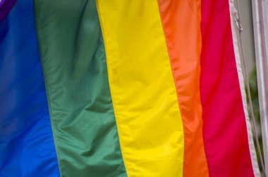 Yakın plan gökkuşağı eşcinsellik gururu bayrağı bir sokakta. Lezbiyen Biseksüel Transseksüel LGBT topluluğunun sembolü bulutlu gökyüzüne karşı rüzgarda sallanıyor. Özgürlük ve eşitlik için sosyal hareket. Boşluğu Kopyala 