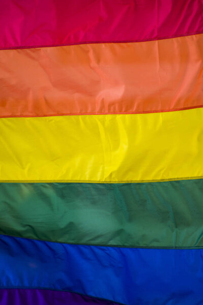 Крупный план радужного гей-флага на улице. Символ ЛГБТ-сообщества лесбиянок-бисексуалов, размахивающих ветром против облачного неба. Социальное движение за свободу и равновесие. Копировальное пространство 