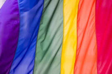 Yakın plan gökkuşağı eşcinsellik gururu bayrağı bir sokakta. Lezbiyen Biseksüel Transseksüel LGBT topluluğunun sembolü bulutlu gökyüzüne karşı rüzgarda sallanıyor. Özgürlük ve eşitlik için sosyal hareket. Boşluğu Kopyala 