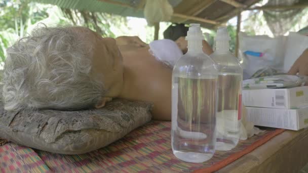 バタンバン カンボジア 2020 病気の老婦人は ボトルナトリウム塩化物注射と薬箱とベッドに横たわっ — ストック動画