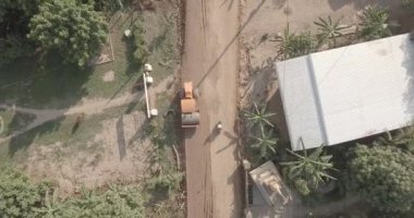 Sabit silindirden yükselen yol yapımı, küçük köydeki kırsal evleri ortaya çıkarıyor.