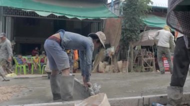 Kampong - Kamboçya - 04-09 - 2018; pürüzsüz bir işçiye yaklaşın ve hava boşluklarını önlemek ve düz bir yüzey oluşturmak için dökülen betonu taşıyın