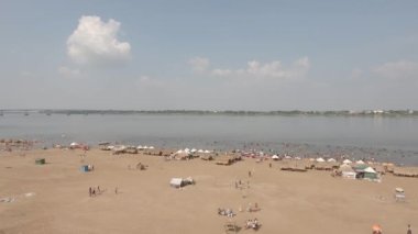 Kalabalıktan oluşan insansız hava aracı görüntüleri yüzmek için toplandı. Kum plajına yayılmış ahşap bungalovlar var.
