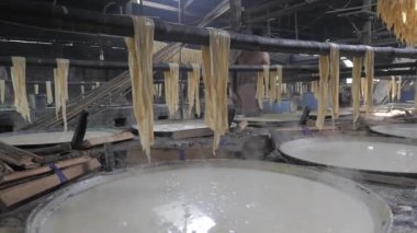 Dev tavaların içinde soya sütünün yüzeyinde ince bir köpük tabakası oluşuyor. Yuba çarşafları kuruması için tavaların üzerinde asılı. (Yakın çekim)