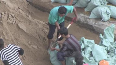 Kampong - Kamboçya - Ekim 2013; Muson yağmurları sırasında selden korunmak için torbaları kumla dolduran gönüllülerin üst görünümü