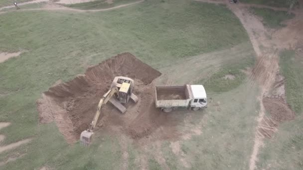 开阔地挖掘机将泥土装入一辆小卡车的空中静态视图 — 图库视频影像