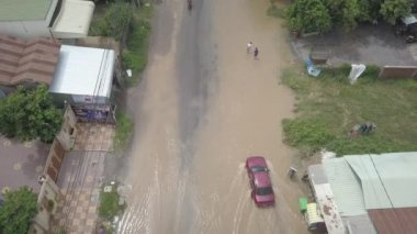Battambang - Kamboçya - 10 - 08 - 2020: su basmış bir caddeden geçen motosiklet araçlarının üzerinden geri geri uç
