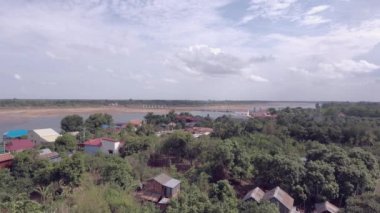 aerial static view of rural village and bridge under construction over river in the background