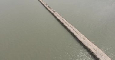 İnsansız hava aracı görüntülerine göre motorlu araçlar nehrin üzerinden bambu köprüsünü geçiyor.