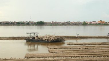 Kampong Cham - Kamboçya - 09 - 5 - 2017: Bambu direklerinin genişliği bir nehir mavnası üzerinde durgun bir mavna boyunca uzanıyordu